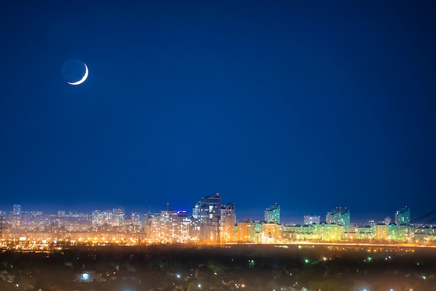 Stadt bei Nacht mit Neumond am dunkelblauen Himmel mit Sternen