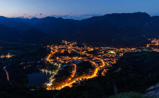 Stadt Smolyan mit Lichtern vor dem Hintergrund der Bergkette der Rhodopen und dunklem Himmel