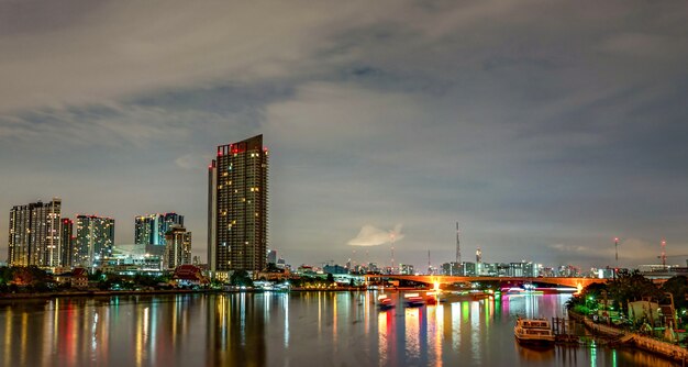 Stadtbild des modernen Gebäudes nahe dem Fluss in der Nacht. Bürogebäude der modernen Architektur. Wolkenkratzer mit Abendhimmel. Nachtfotografie des Flussufergebäudes.
