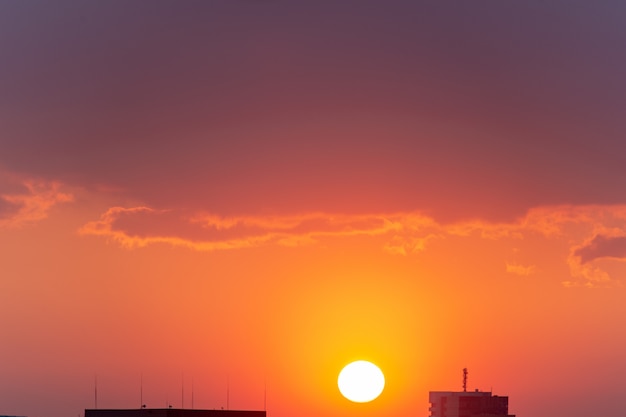 Stadtbild und Sonnenuntergang mit Silhouetten von Häusern.