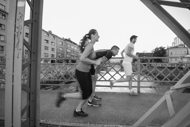 Stadtsport, gesundes junges Paar, das am sonnigen Morgen über die Brücke in der Stadt joggt