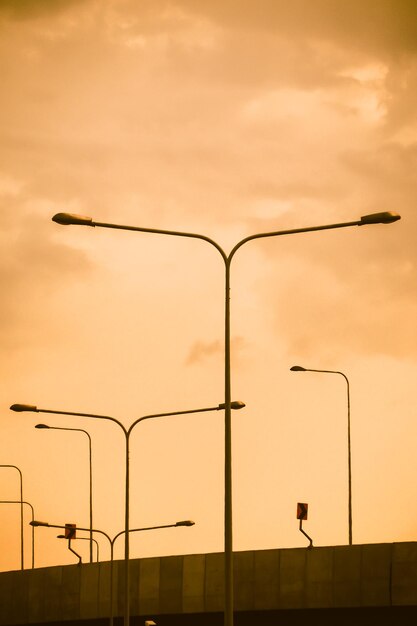 Stadtstraße und elektrischer Pfosten, Landschaft, Stadtbild gegen orangefarbenen Himmel bei Sonnenuntergang Sonnenaufgang Hintergrund