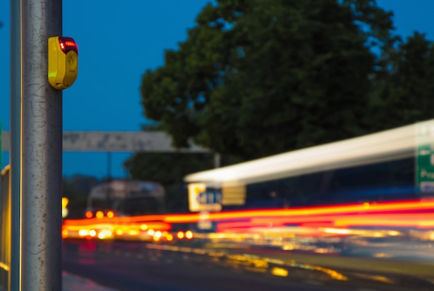 Stadtverkehr am Abend, Wartezeitknopf-Zebrastreifenabschluß herauf Gelb und Autolichter