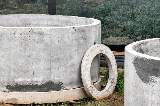 Stahlbetonringe für die Installation von unterirdischen Brunnen auf der Baustelle. Stahlbetonprodukte für die Einrichtung der unterirdischen Kommunikation. Kanalisation und Sanitär.