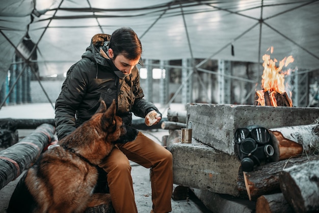 Stalker alimentando um cachorro, conceito de apocalipse. Estilo de vida pós-apocalíptico em ruínas, dia do juízo final, dia do julgamento