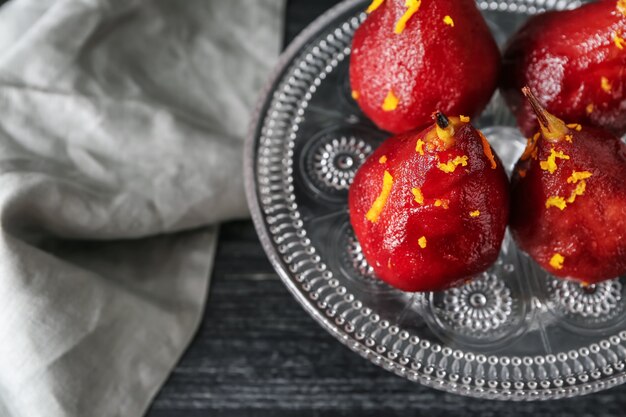 Stand com deliciosas peras escaldadas em vinho tinto na mesa de madeira