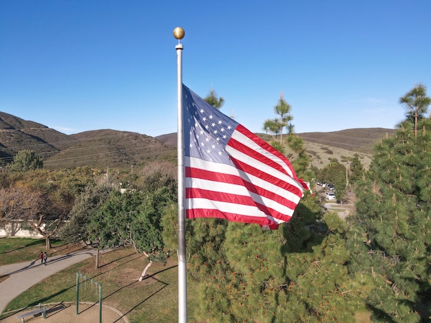 Stange mit wehender ruhmreicher amerikanischer Flagge, umgeben von Bäumen auf dem Gipfel eines Berges