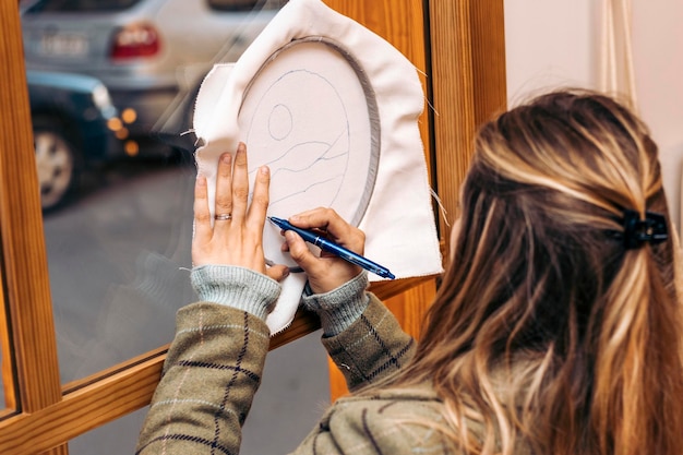 Stanznadel-Workshop Junge Frau, die sich auf die Fensterzeichnung stützt