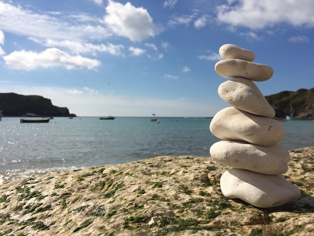 Stapel auf Kieselsteinen auf Felsen am Meer gegen den Himmel
