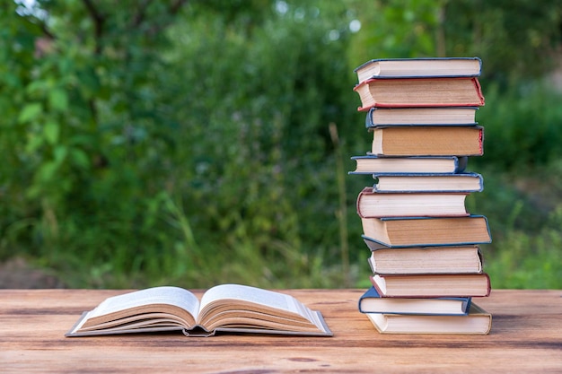 Stapel Bücher auf Holztisch über Naturhintergrund im Freien