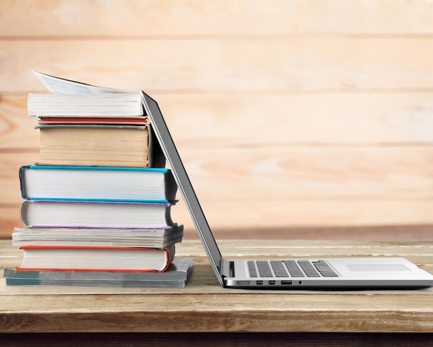 Foto stapel bücher mit laptop auf holztisch