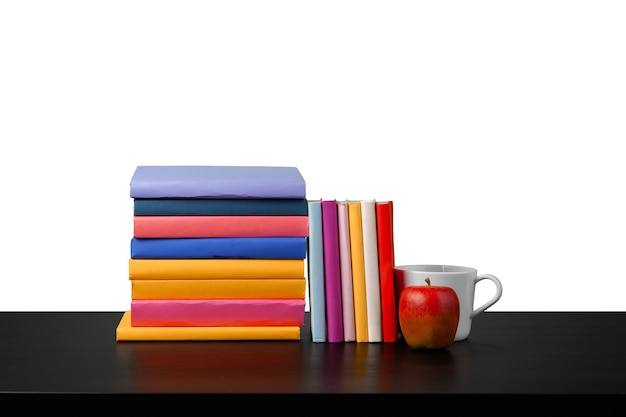 Stapel Bücher und Apfel auf Tischplatte vor weißem Hintergrund