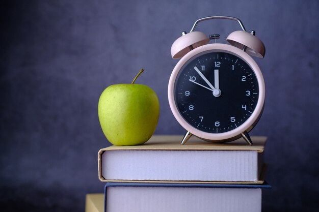 Stapel Bücher und Uhr auf Tisch nah oben.