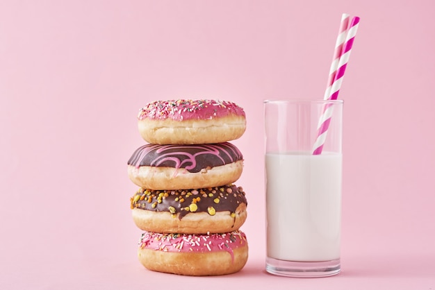 Stapel bunte Donuts verziert und Glas Milch auf rosa