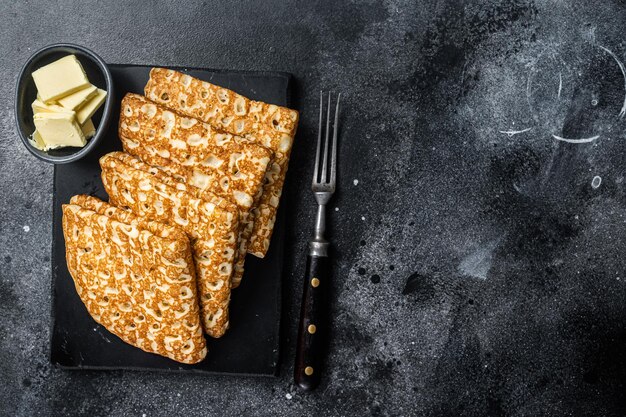 Stapel Crêpes mit Butter auf einer Marmorplatte Schwarzer Hintergrund Draufsicht Kopierbereich