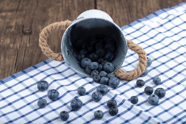 Stapel der frischen Blaubeeren aus dem Metalleimer auf hölzernem Hintergrund.