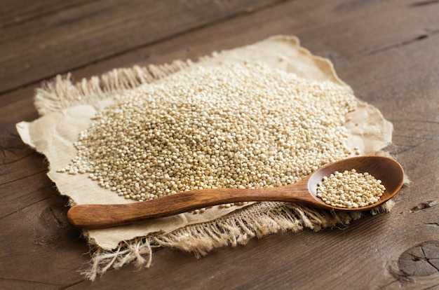 Stapel der weißen Quinoa mit einem Löffel auf einem Holztisch schließen oben