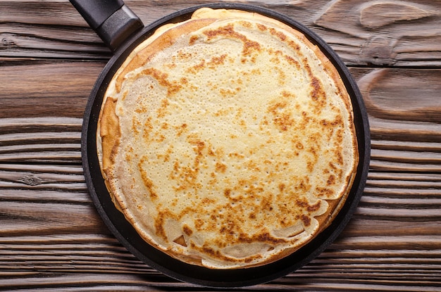 Stapel französischer Crpes in der Pfanne auf dem Küchentisch aus Holz