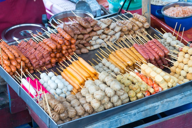 Stapel gebratener Fleischball und -wurst im Aluminiumbehälter.