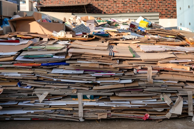 Stapel gefalteter gebrauchter Papp- und Papierschachteln, die für das Recycling gelagert werden