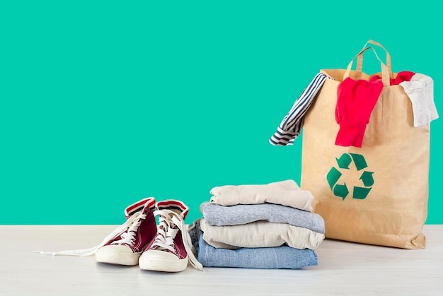 Stapel Kleider Turnschuhe und Tasche mit recycelbarem Schild auf Holztisch