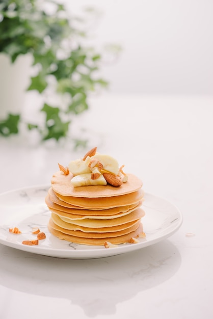 Stapel leckere Pfannkuchen mit Schokolade, Honig, Nüssen und Bananenscheiben auf Teller