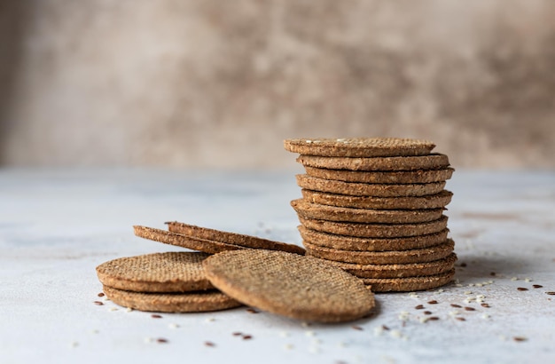 Stapel leckerer Cracker mit Sesam und Leinsamen auf grauem Hintergrund Gesunder Snack