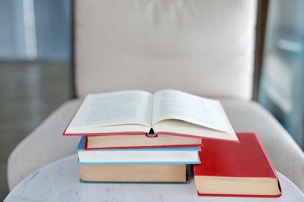 Stapel Lehrbücher auf Schreibtisch mit offenem Buch auf die Oberseite im Bibliotheksraum