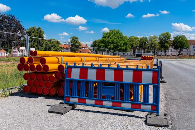 Stapel oranggelber PVC-Leitungsrohre hinter der tragbaren Kunststoffbarriere