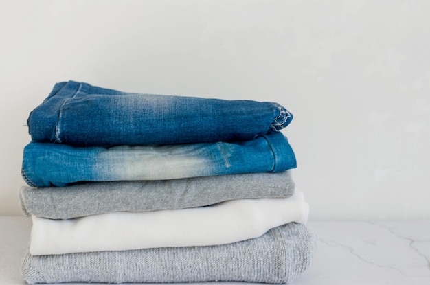 Stapel Pullover und Blue Jeans auf grauem Hintergrund