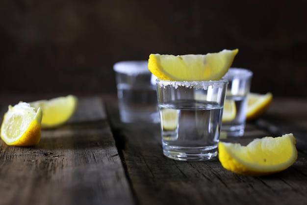 Stapel Tequila mit Salz und Zitrone auf Holzhintergrund