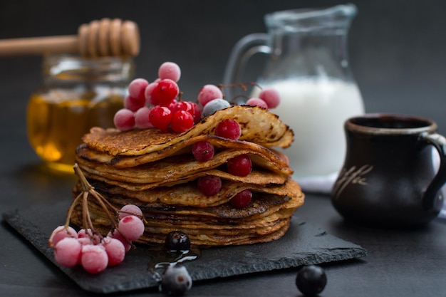 Stapel traditioneller russischer Pfannkuchen mit Honig auf schwarzem Hintergrund mit hausgemachten russischen dünnen Pfannkuchen Russische Nationalküche