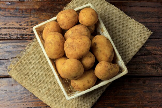 Stapel von den frischen und rohen Kartoffeln geerntet von der Plantage und in rustikalen Kasten auf Holztisch gelegt