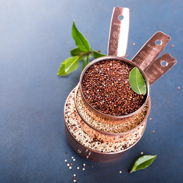 Stapel von drei kupfernen Messbechern mit gemischter roher Quinoa