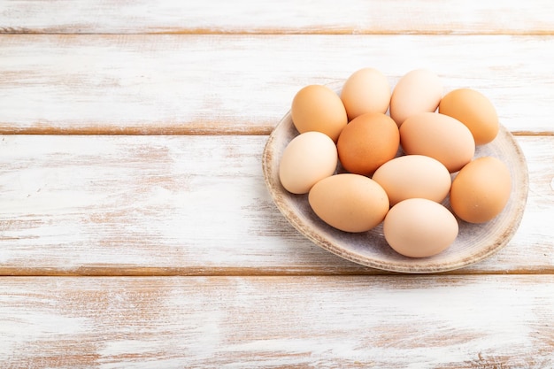 Stapel von farbigen Eiern auf Platte auf einem weißen hölzernen Hintergrundseitenansicht-Kopienraum Beschneidungspfad eingeschlossen