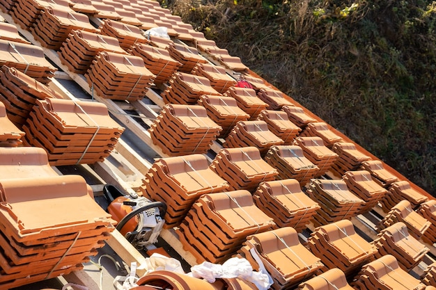 Stapel von gelben keramischen Dachziegeln zum Abdecken des Daches von Wohngebäuden im Bau.