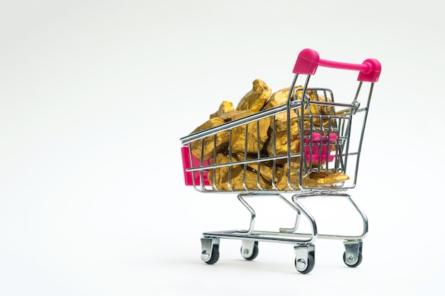 Stapel von goldnuggets oder von golderz im warenkorb oder in der supermarktlaufkatze