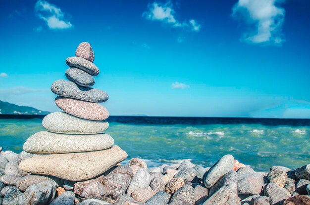 Stapel von Kieselsteinen am Meer gegen den blauen Himmel