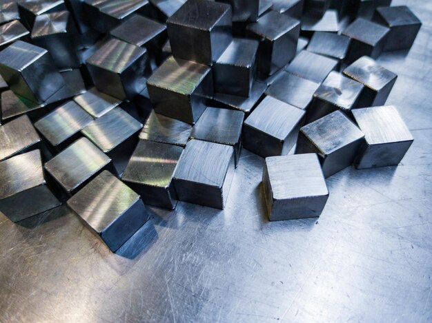 Stapel von kleinen maschinell bearbeiteten glänzenden Stahlwürfeln auf Metalloberfläche