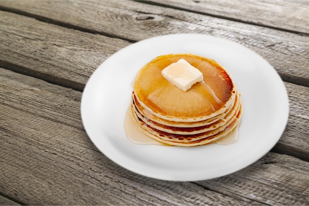 Stapel von kleinen Pfannkuchen in Sirup im Hintergrund