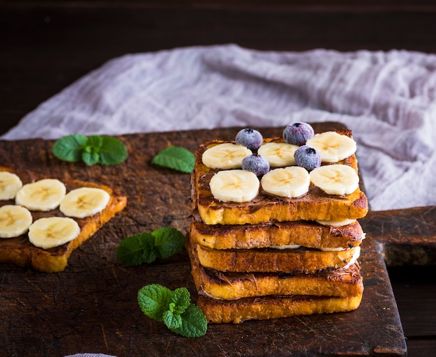 Stapel von quadratischen Scheiben des gebratenen Brotes mit Schokolade und Banane