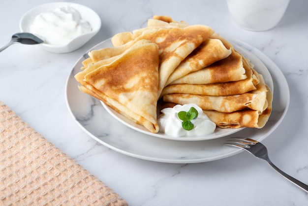 Stapel von russischen dünnen Pfannkuchen Blini mit frischer Sauerrahm