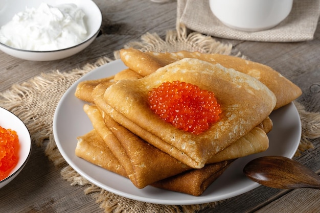 Stapel von russischen dünnen Pfannkuchen Blini mit rotem Kaviar auf einem alten Holztisch Maslenitsa