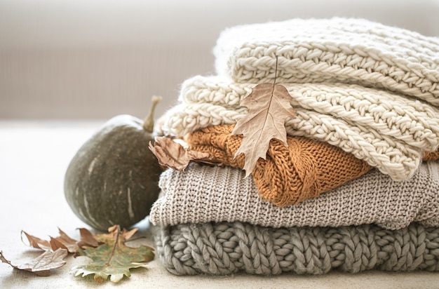 Stapel warmer Strickwaren aus Herbstgarderobe und Kürbis hautnah.