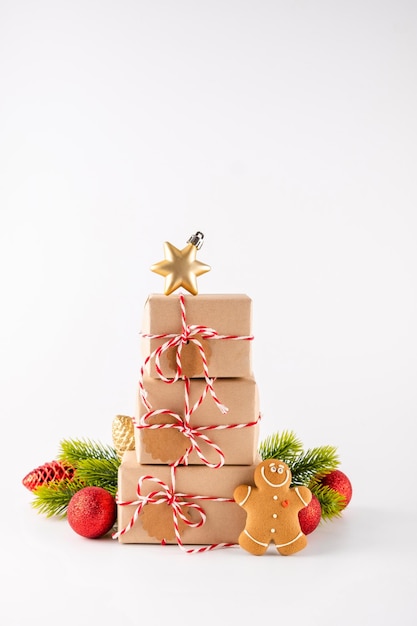 Stapel Weihnachtsgeschenkboxen aus Bastelpapier mit knusprigen Lebkuchenmännerplätzchen und heller Dekoration. Frohe Weihnachten-Konzept auf weißem Hintergrund