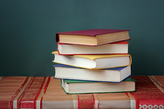 Stapelbücher mit Farbabdeckungen auf dem Tisch mit einer roten Tischdecke.