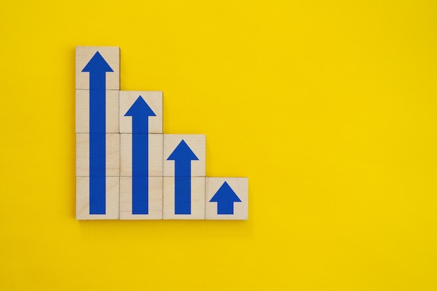 Stapeln von Holzblöcken als Stufentreppe mit wachsendem Pfeil nach oben im Konzept Geschäftswachstumserfolg