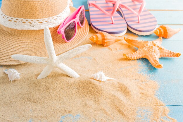 Starfish und Hut auf Sand auf blauem Bretterboden, Sommerferien im Strandkonzept