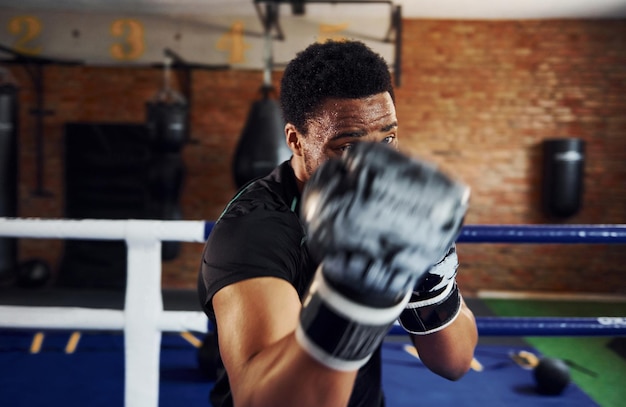 Starke afroamerikanische Boxer in sportlicher Kleidung trainieren im Fitnessstudio