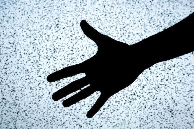 Starke dunkle hochkontrastreiche Silhouette einer ausgestreckten Hand auf einem hellen weißen Fernsehbildschirm